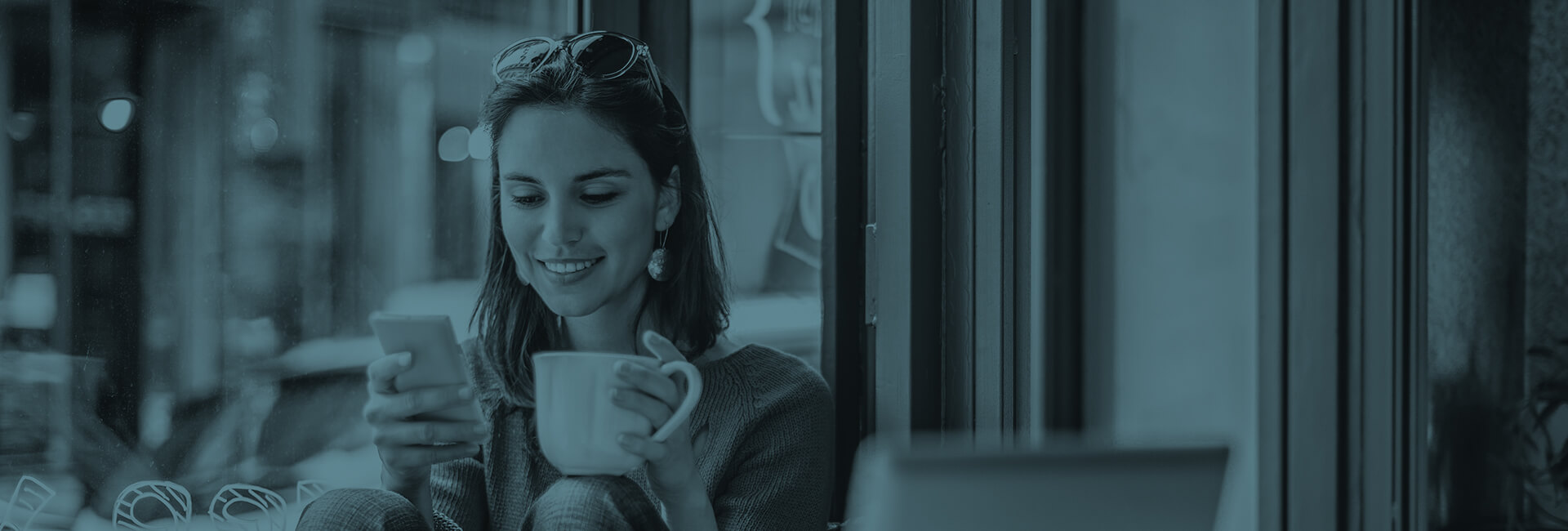 smiling woman drinking coffee while looking at her phone