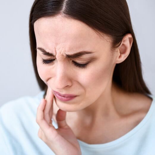 woman holding her jaw in pain