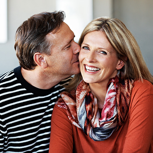 man kissing smiling woman on cheek