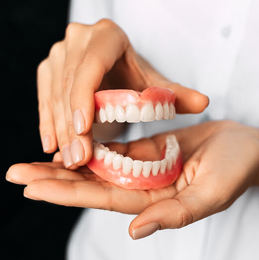 person holding a set of dentures