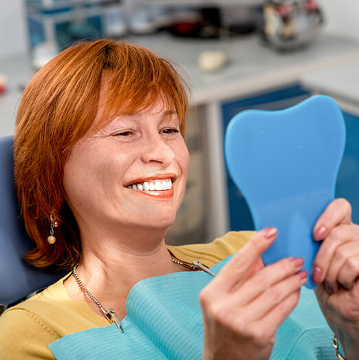 woman examining her smile in a mirror