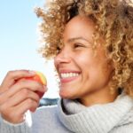 woman eating an apple, which is on the list of foods that clean teeth